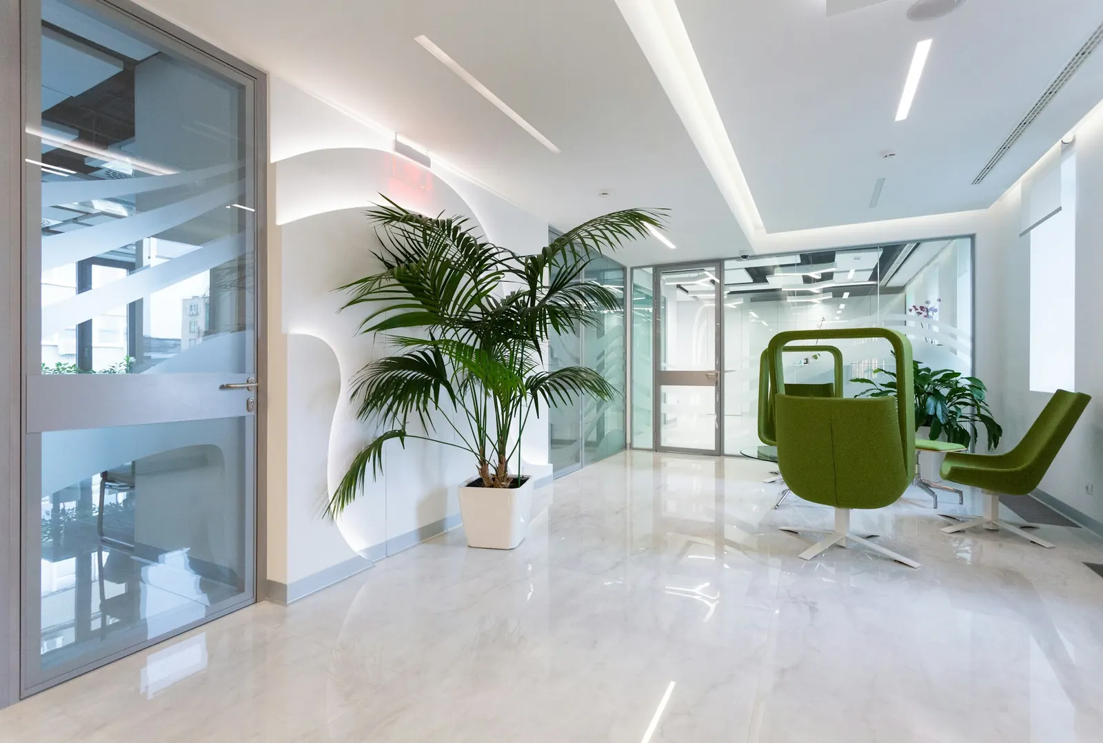 A bright office atrium with white floor tiles and plants