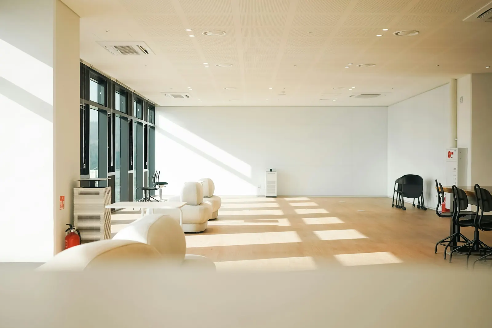 A bright, empty office lounge with morning sun across a clean floor